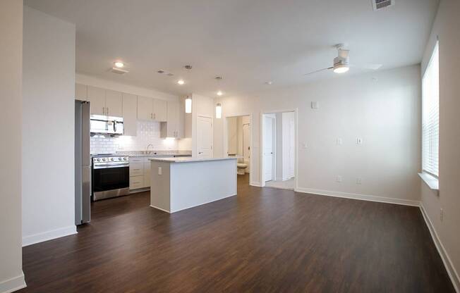 A spacious kitchen with white cabinets and a wooden floor.