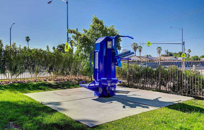 A blue object is placed on a concrete slab in a grassy area.