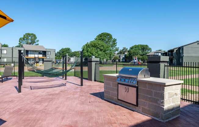 barbecue area and hammock lounge at Fusion Fort Worth in Haltom City, TX next to large green field with black iron fence.
