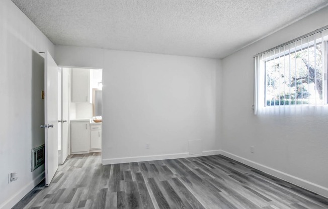 a bedroom with hardwood floors and white walls