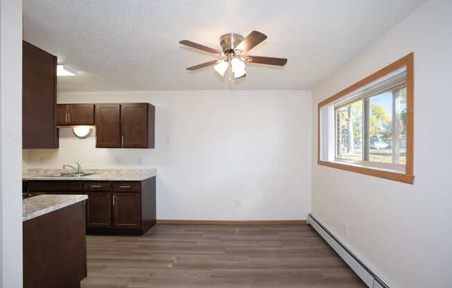 an empty kitchen with a ceiling fan and a window. Fargo, ND Country Club Apartments