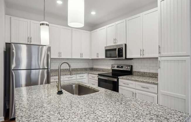 A kitchen with a granite countertop and stainless steel appliances.
