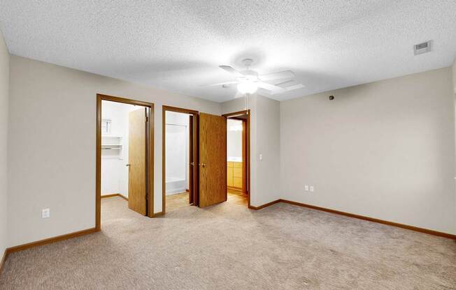 A room with a carpeted floor and a ceiling fan.