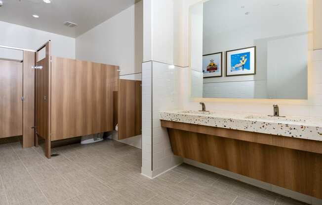 a public restroom with two stalls and two sinks and a mirror