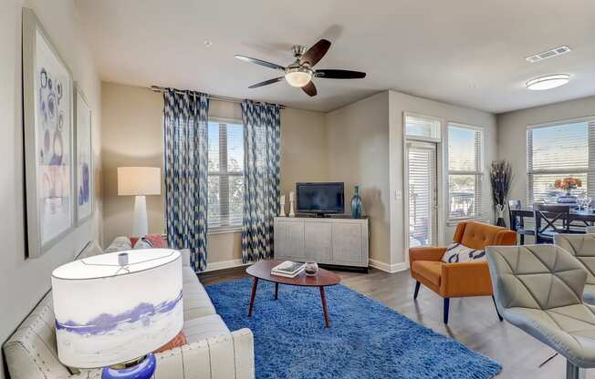 a living room with a blue rug and a ceiling fan