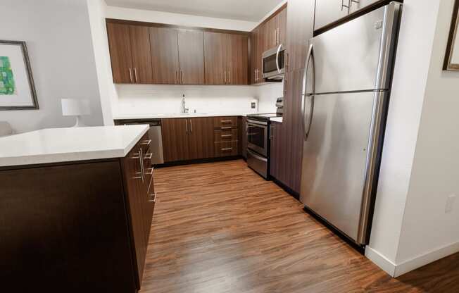 an empty kitchen with stainless steel appliances and wooden flooring