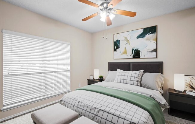 a bedroom with a large window and a ceiling fan