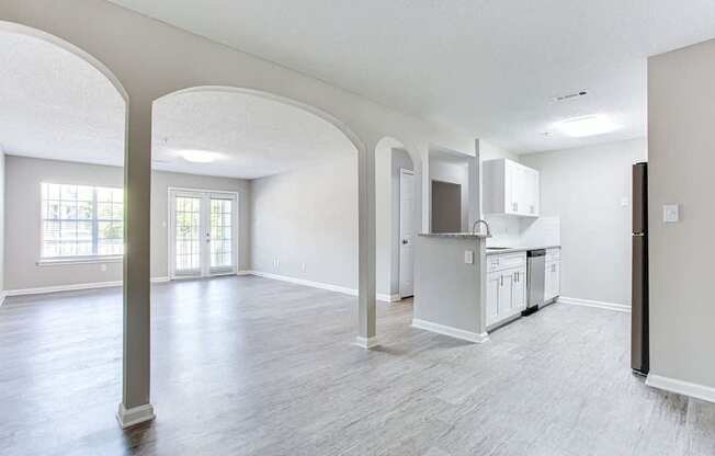 A spacious living room with a kitchen area in the background.