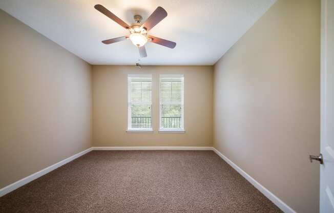 an empty room with a ceiling fan and a window