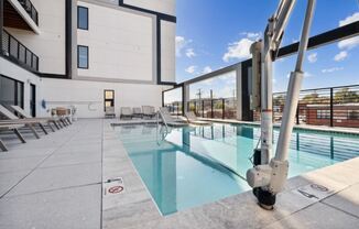 a pool with lounge chairs and a building in the background at The Box, Virginia, 23224