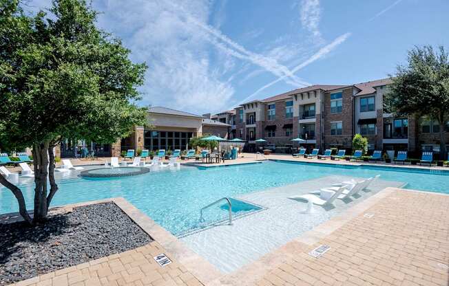 a large swimming pool with lounge chairs in front of an apartment building