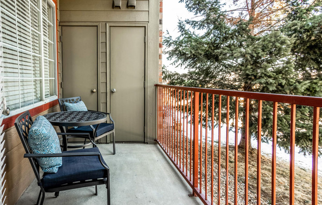 a balcony with a table and chairs and a door to a patio at The links at Plum Creek Apartments, Castlerock