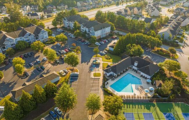 an aerial view of a neighborhood with a swimming pool and cars in a parking lot