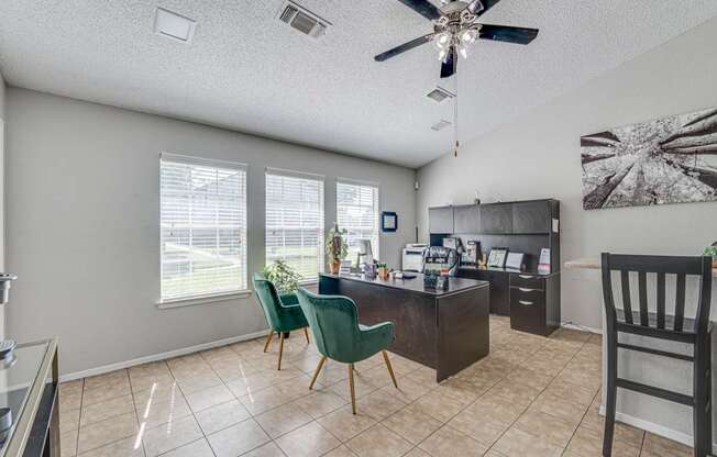 A room with a ceiling fan and a table with chairs.