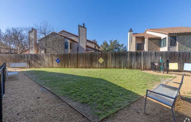 A dog park with a wooden fence and a bench at Preston Oaks Apartments in Dallas, TX.