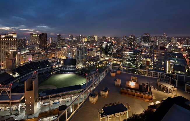 A rooftop bar overlooks a city skyline at night.