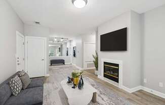 A modern living room with a grey couch and a fireplace.