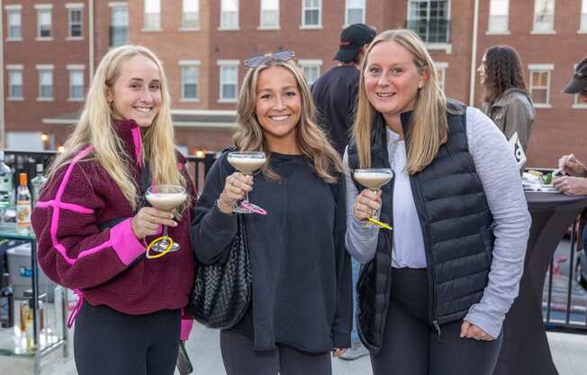 three women holding wine glasses and posing for a picture