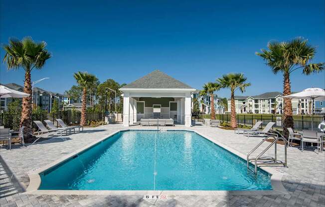 A pool area with a small building and palm trees.