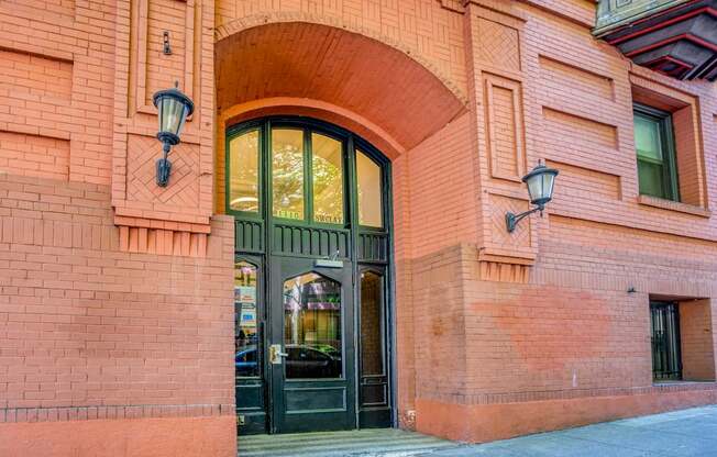 A red brick building with a black door and two lamps on either side.