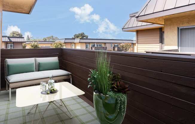 a balcony with a couch and a table and a potted plant