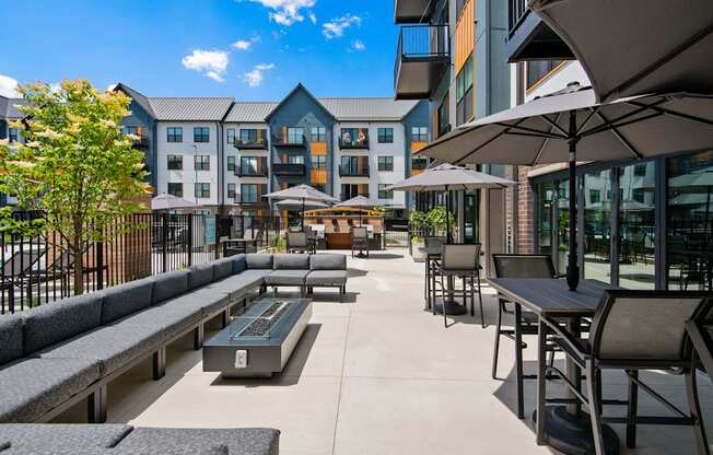 A patio area with tables and chairs and umbrellas.