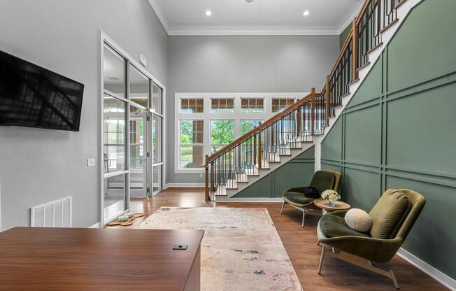 Resident lounge seating tucked beneath a statement staircase, offering a comfortable space to connect, relax, or enjoy a quiet moment indoors.