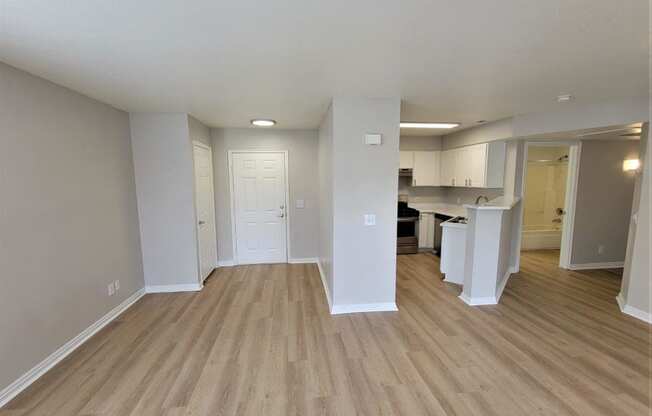 an empty living room and kitchen with wood flooring