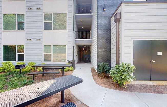 A white building with a grey roof and a black bench in front of it.