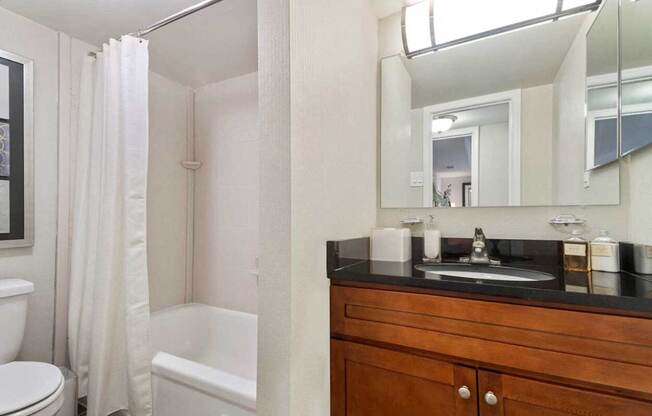 A bathroom with a toilet, a bathtub, a sink and a mirror.