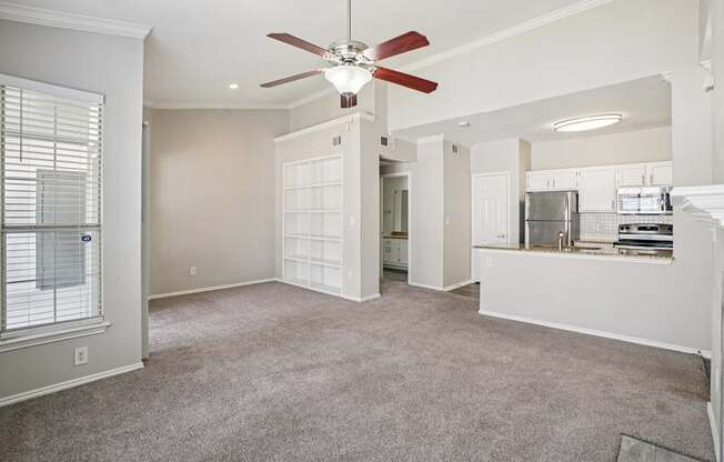 A room with a ceiling fan and carpeted floor.