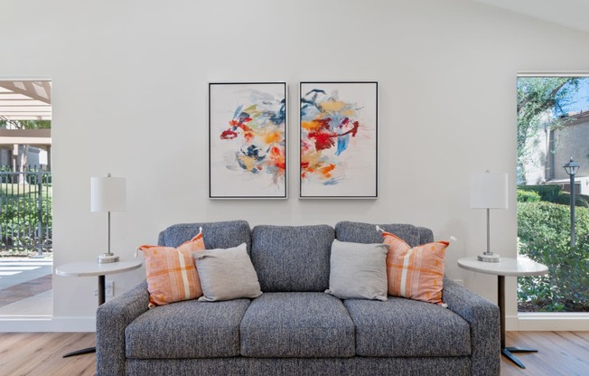a living room with a couch and two paintings on the wall