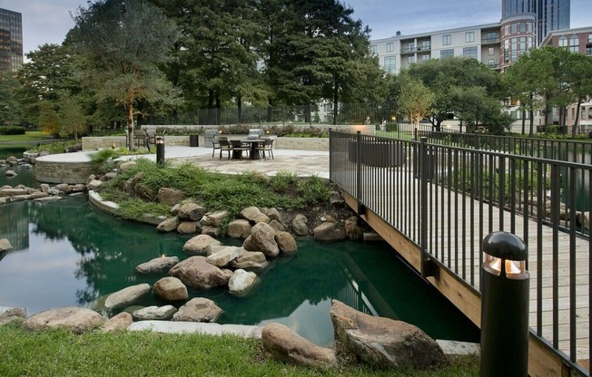 a bridge over a pond in a park with rocks