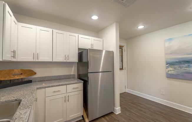 a kitchen with white cabinets and a stainless steel refrigerator