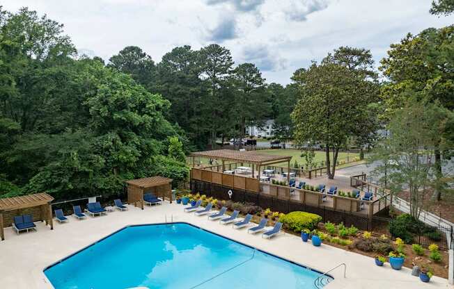 A large swimming pool surrounded by trees and lounge chairs. at Mill House at East Cobb, Marietta, GA