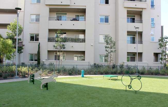 A playground with a slide, swings and a ball pit in front of apartment buildings.