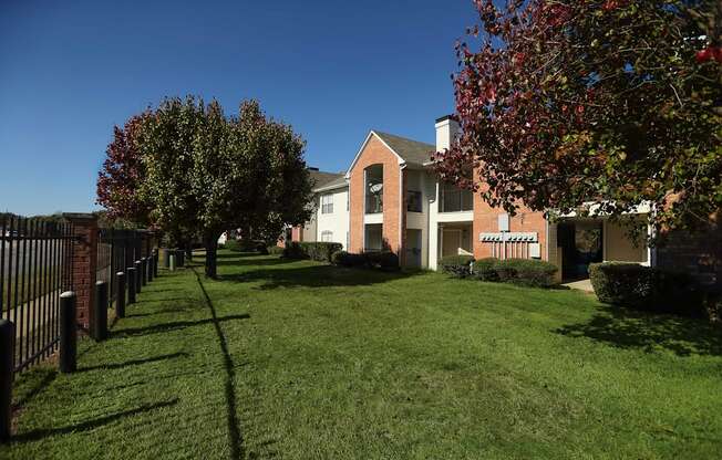 View of gated property, exterior building, and lush grass and trees