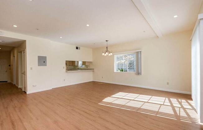 A spacious room with wooden floors and a large window.