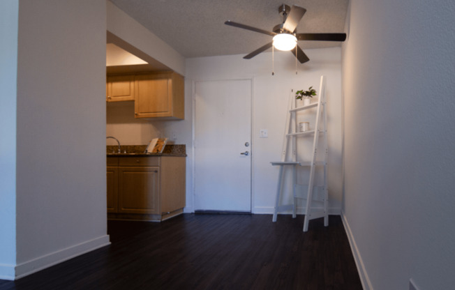A room with a ceiling fan and a ladder against the wall.