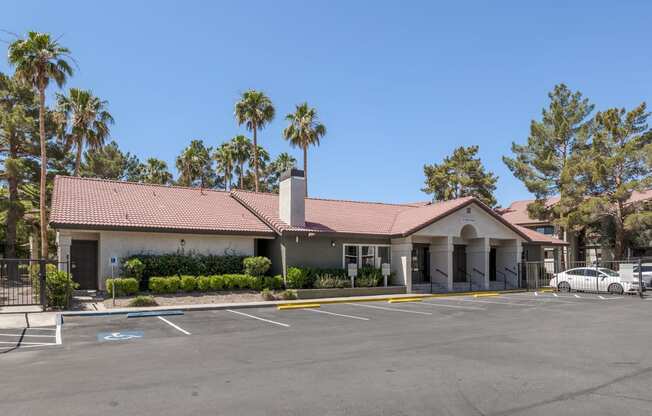 an empty parking lot in front of a building with palm trees