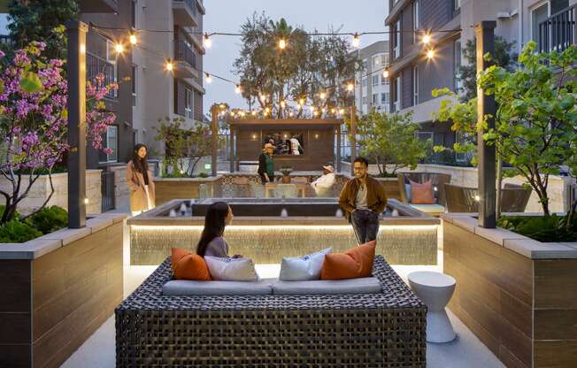 a couple sitting on a couch in front of a pool in an apartment complex