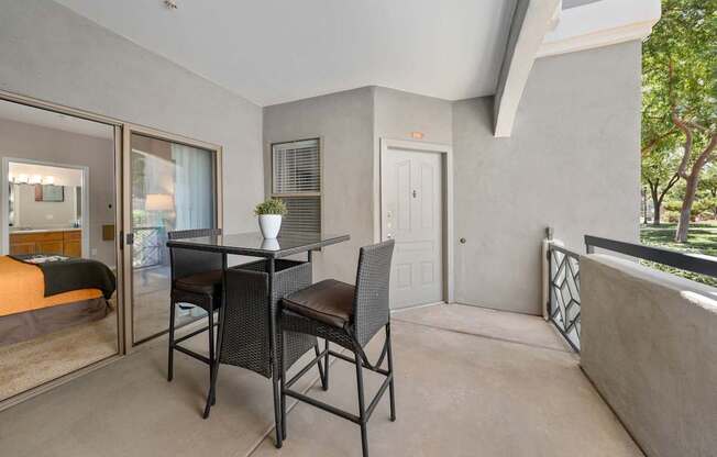 A patio with a table and chairs overlooking a tree.