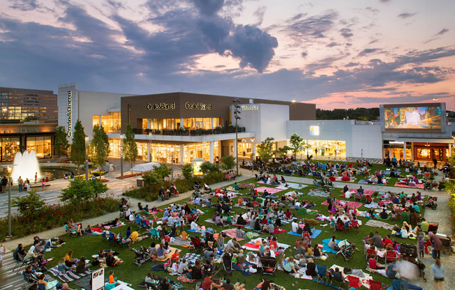 A large group of people are sitting on the grass in front of a building.