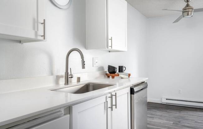 a white kitchen with white cabinets and a stainless steel sink