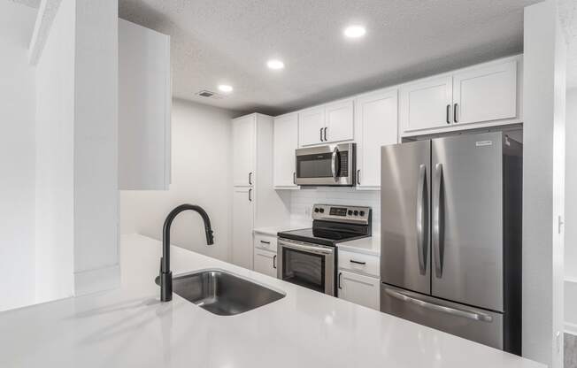 a kitchen with white cabinets and stainless steel appliances