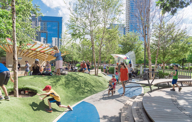 Klyde Warren Park with children and adults playing on a sunny day