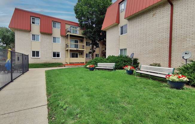 two benches in a yard in front of an apartment building