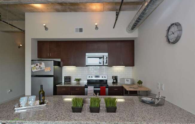 A kitchen with a granite countertop and a clock on the wall.