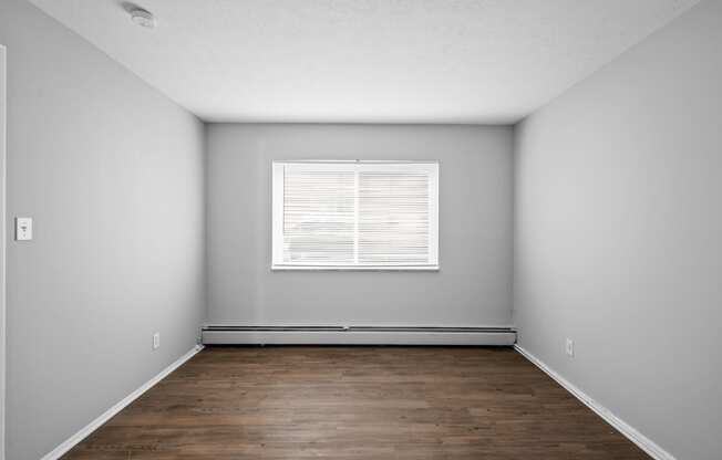 an empty room with wood floors and a window