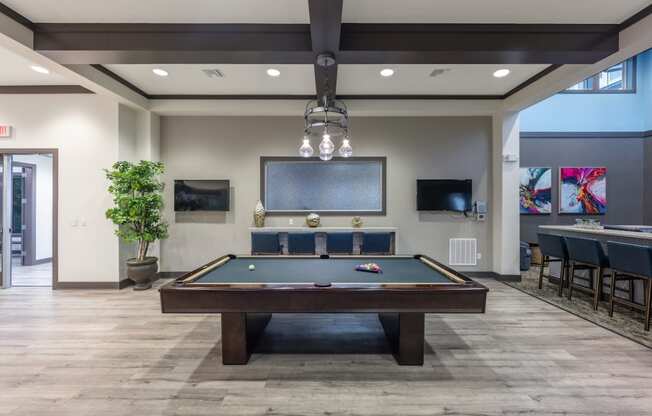 a pool table in the lobby of a clubhouse with a bar and a television